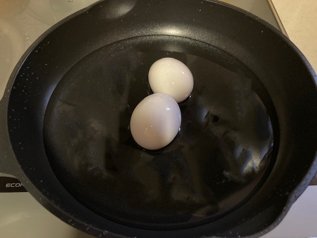 フライパンに卵と水を入れる